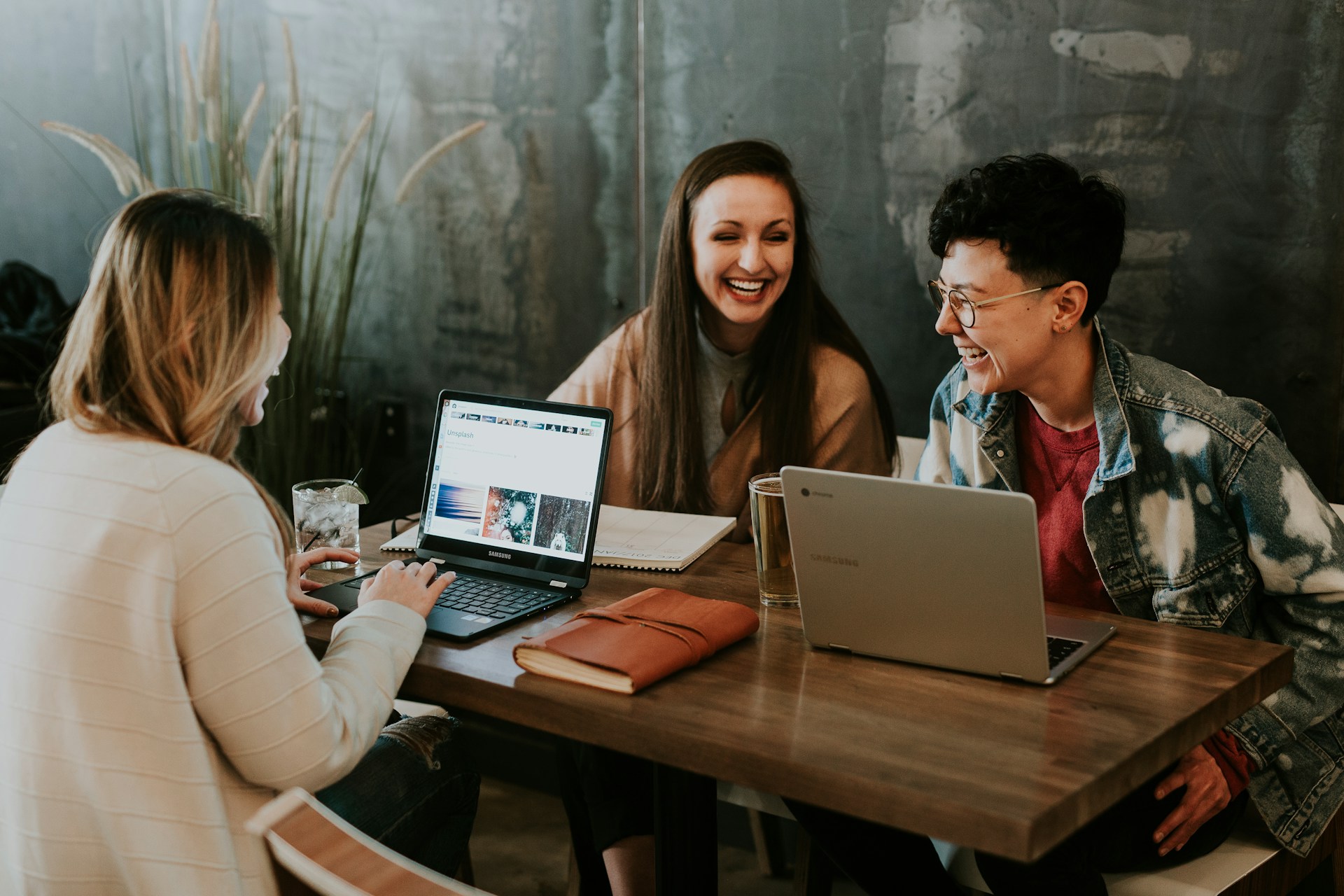 Co-workers laughing and connecting at a table with laptops